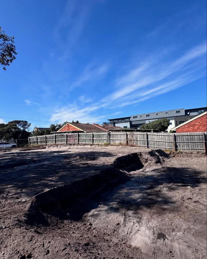 Cleared dirt block with a shallow trench beside a timber fence