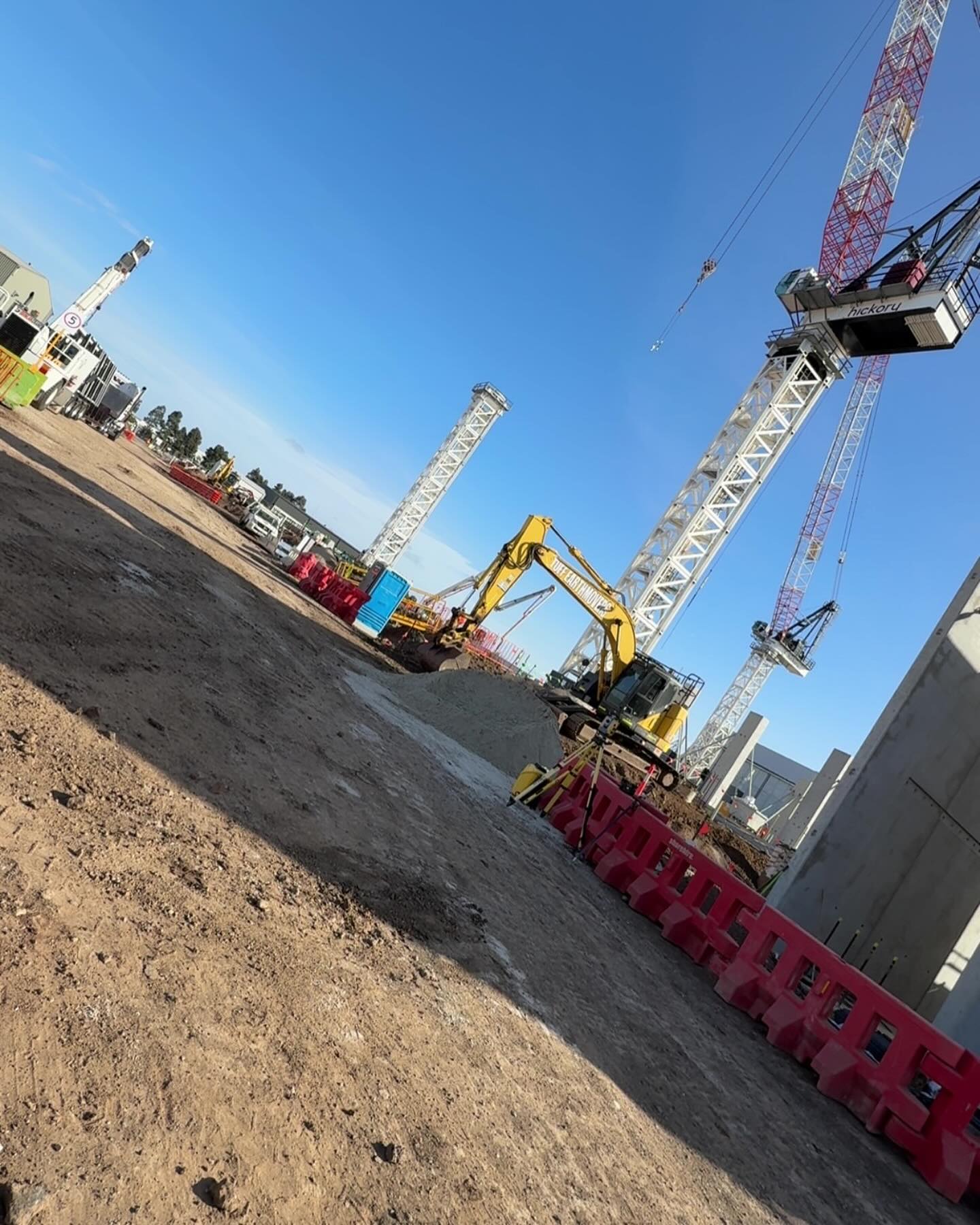 Excavators on a large commercial site with tower cranes behind